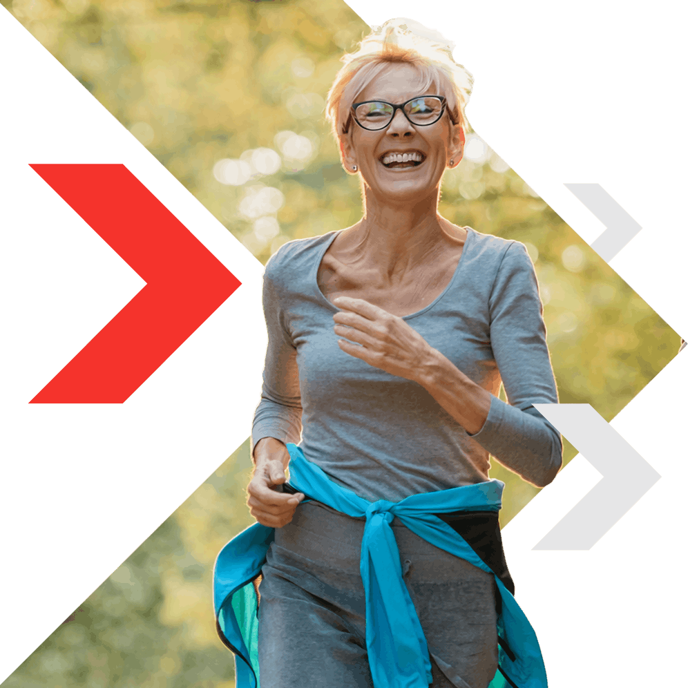 A woman running outdoors along a tree-lined path, wearing sportswear and glasses.